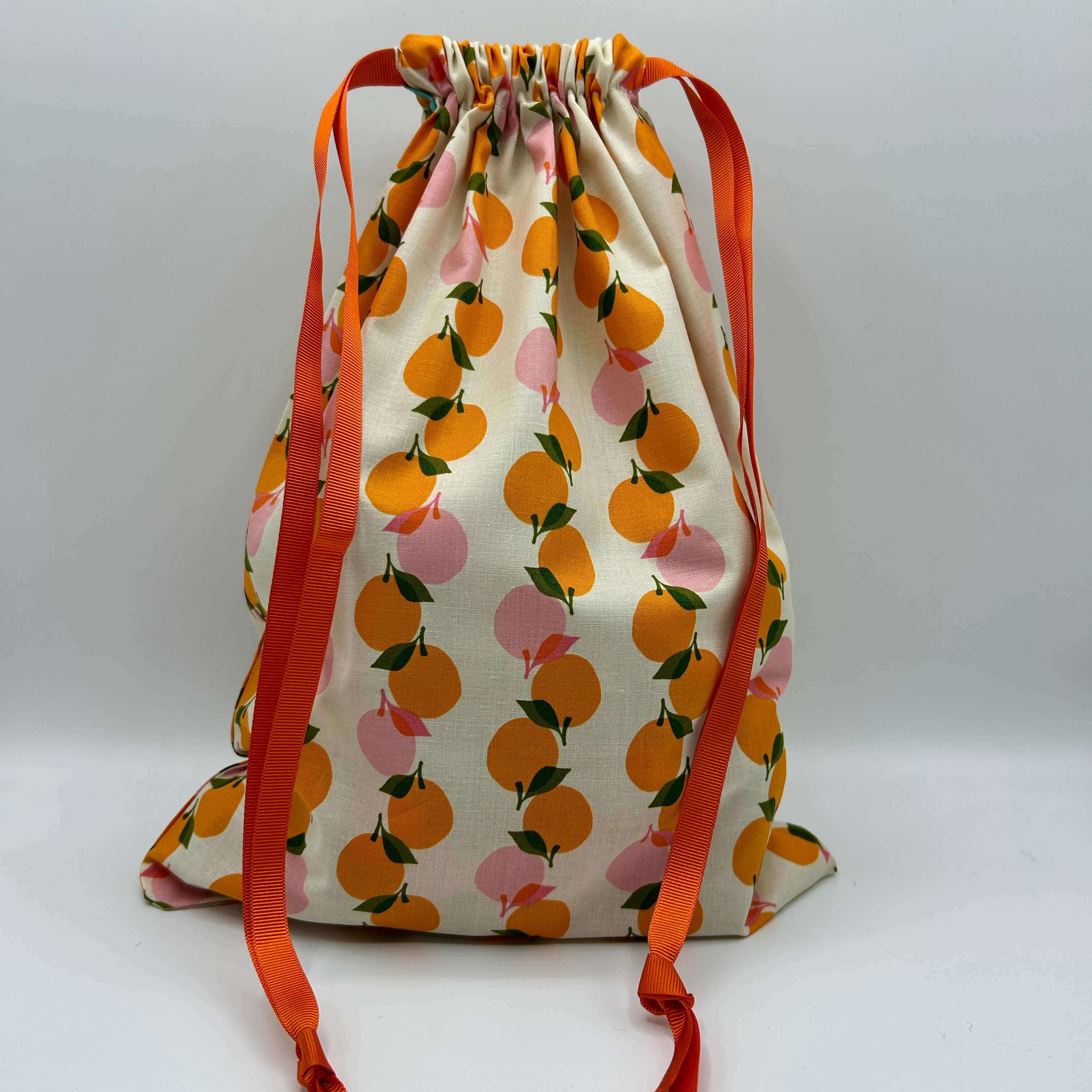 Drawstring bag with fruit pattern and orange drawstrings on a white background