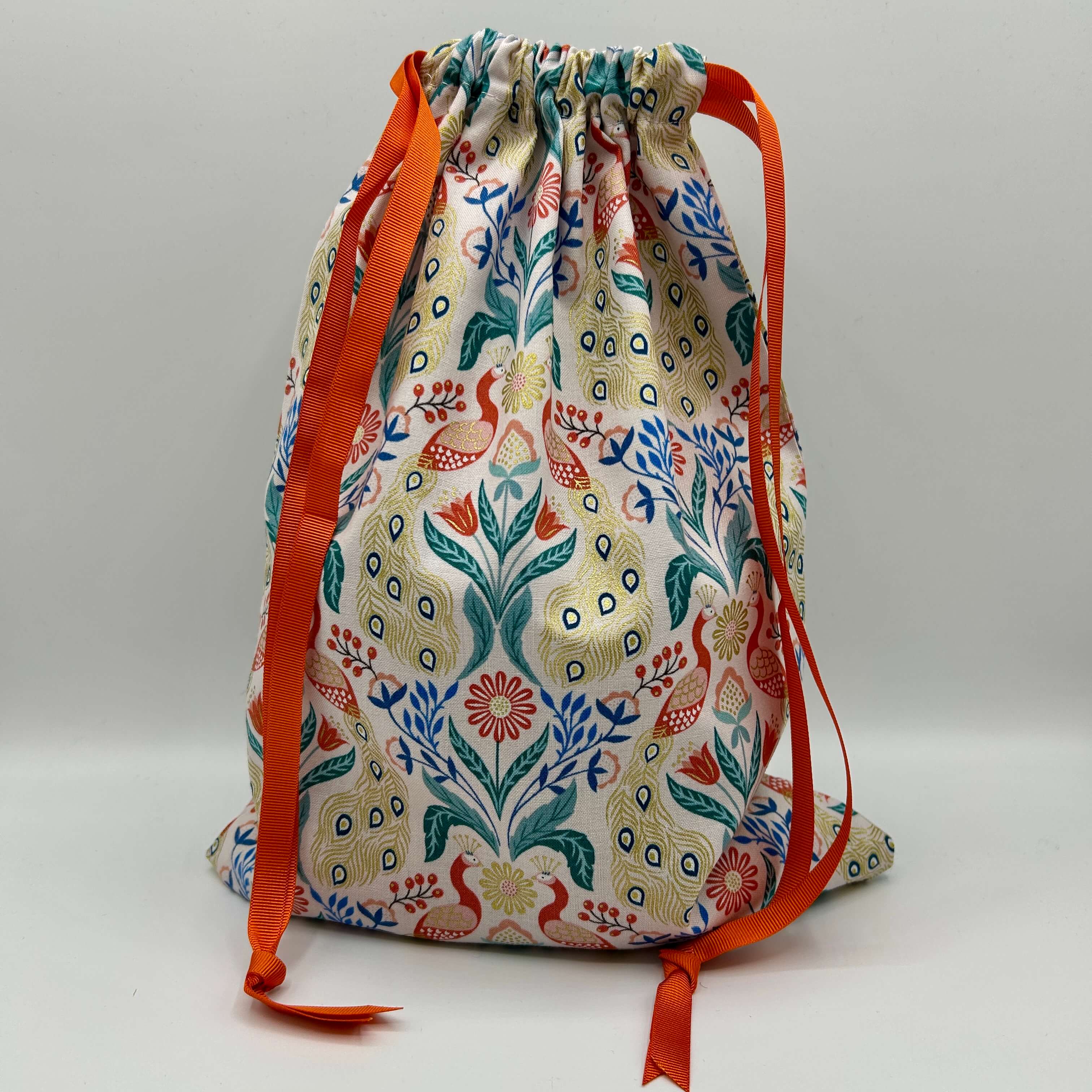 Drawstring bag with floral pattern and orange drawstrings on a light gray background