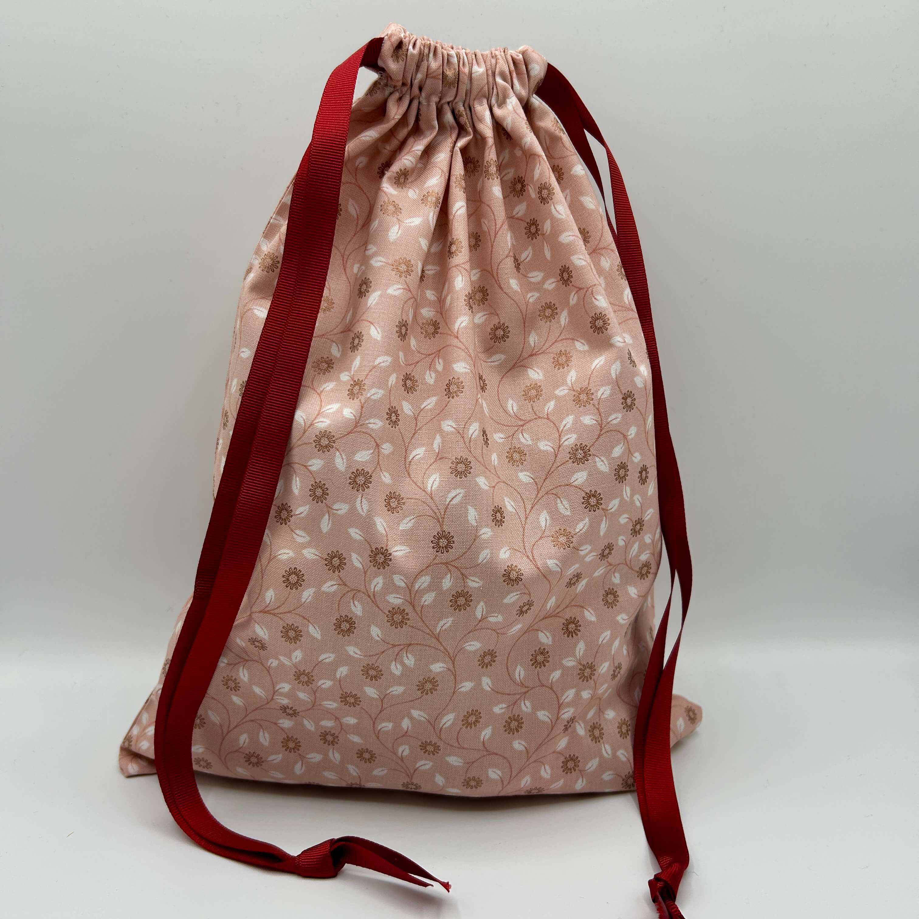 Drawstring bag with floral pattern and red drawstrings on a white background
