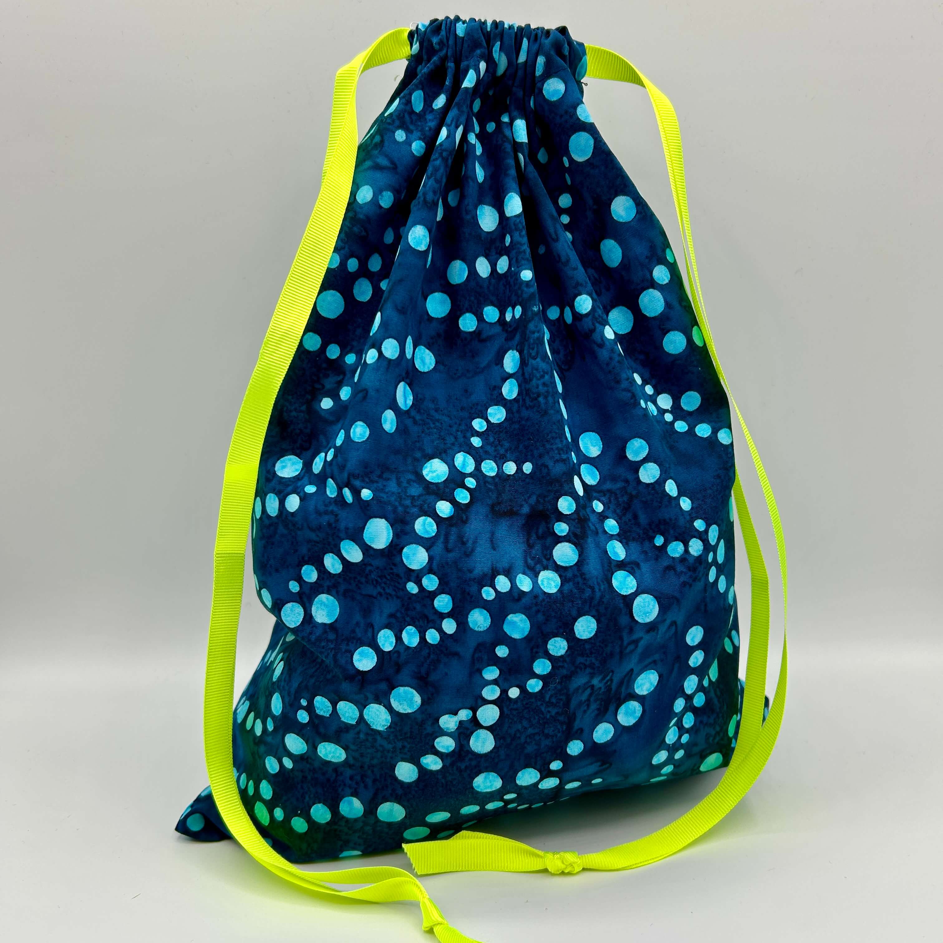 Drawstring bag with blue pattern and green drawstrings on a gray background
