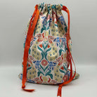 Drawstring bag with floral pattern and orange drawstrings on a light gray background