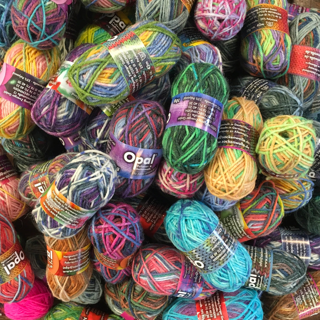 A pile of multi coloured mini balls of 4ply yarn